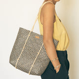 A woman wearing handmade rattan straw shoulder bag suitable for summer boho chic style with black and white colour and ethnic pattern