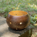 Handcrafted coconut shell tea light holder with star-shaped cutouts and a gold-painted interior, sustainably made in Bali from leftover coconut shells