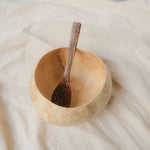 Natural white coconut bowl with a matching coconut wood spoon, showcasing an eco-friendly, handcrafted design with a unique ivory-toned shell