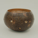 Handcrafted coconut shell tea light holder with star-shaped cutouts and a gold-painted interior, sustainably made in Bali from leftover coconut shells